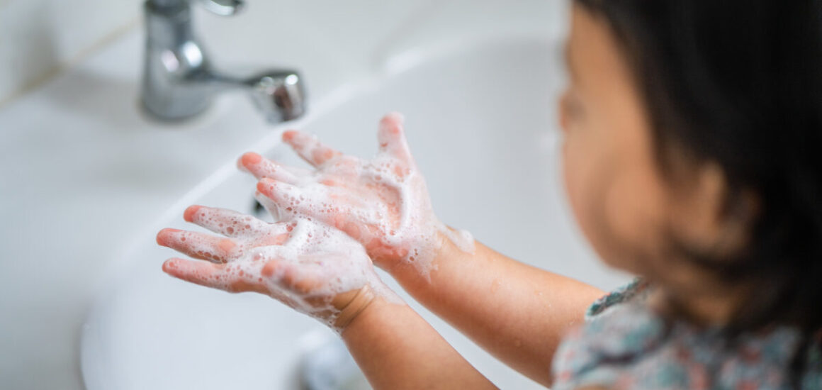 Southeast Asian female kid wash her hands at the lavatory to prevent virus and germs